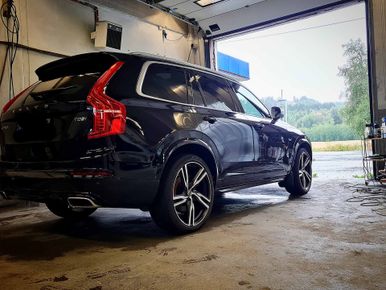 Svart bil står i vaksehall med åpne port