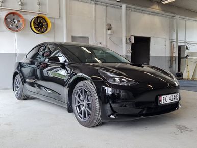 Svart bil i vaskehall med hvite vegger